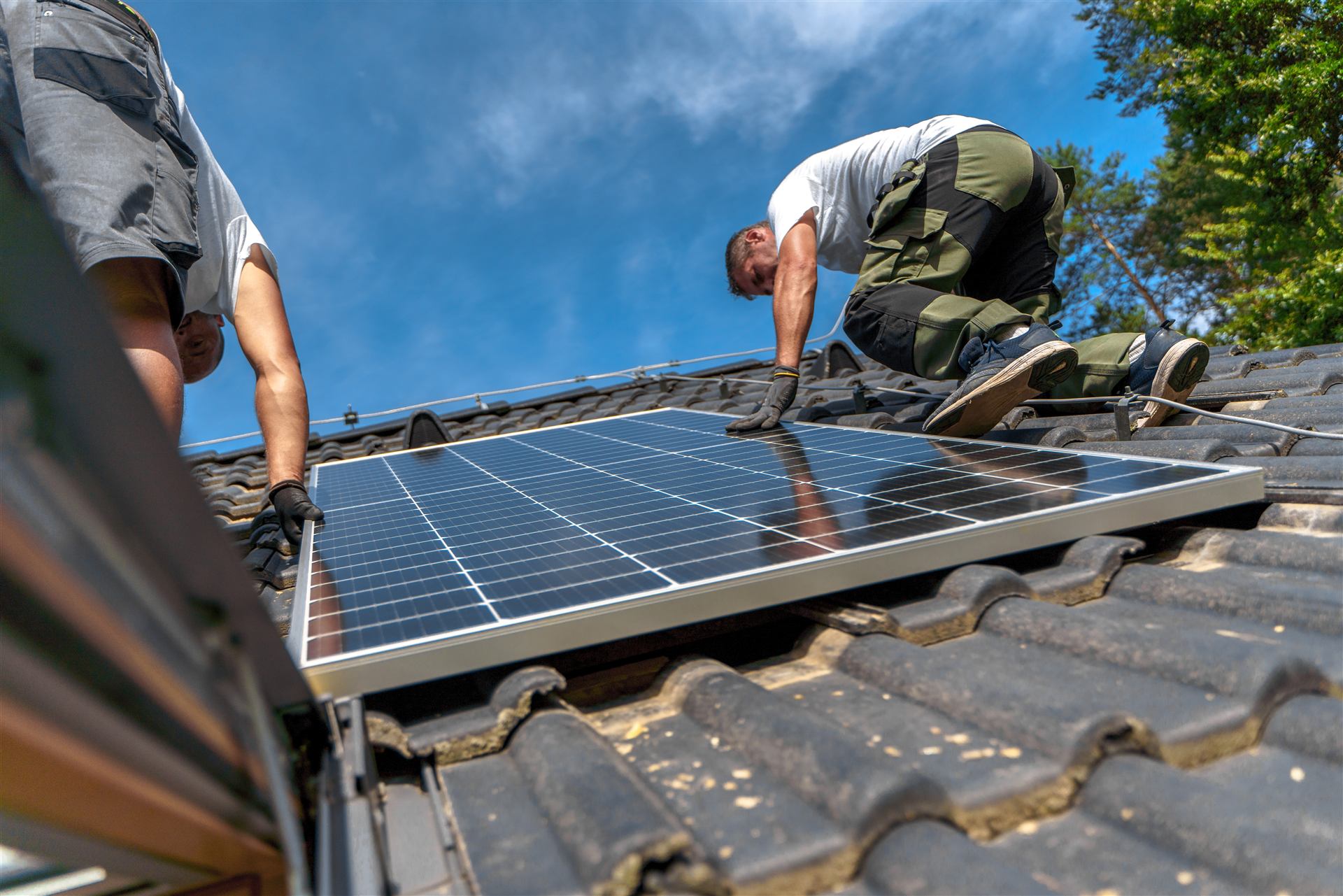 Monteure installieren Solarmodule auf einem Ziegeldach